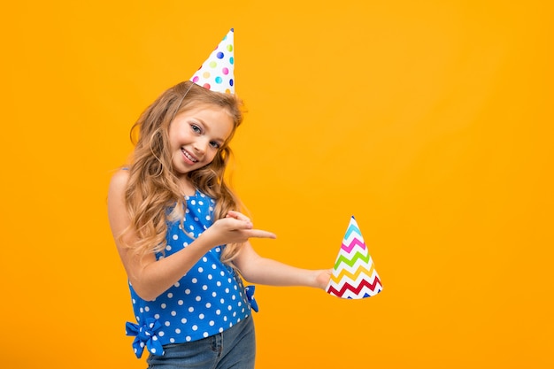 Bambina piacevole con una festa di compleanno isolata sulla parete bianca