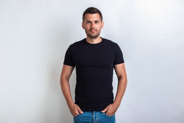 Nice man wearing in black t-shirt standing holding his arms in pocket, seriously looking at the camera