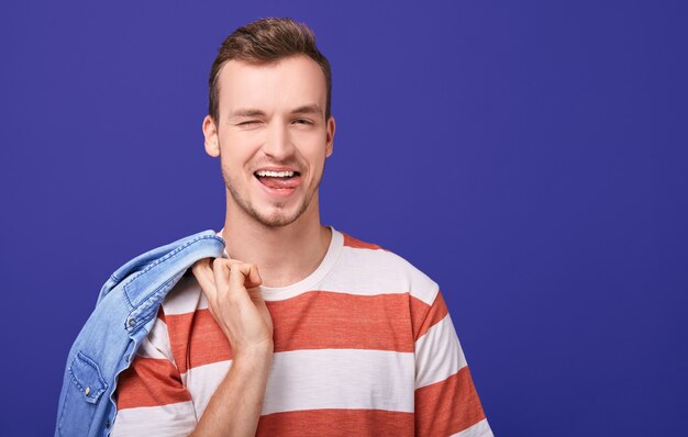 Nice man with protruding tongue looks straight and winks with one eye