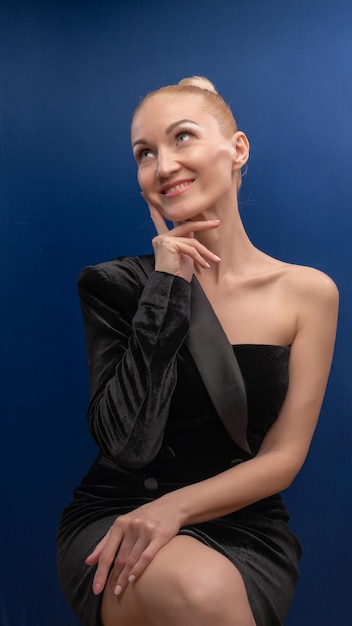 A nice mature girl sits on a chair lovely in a black suit with a European face background