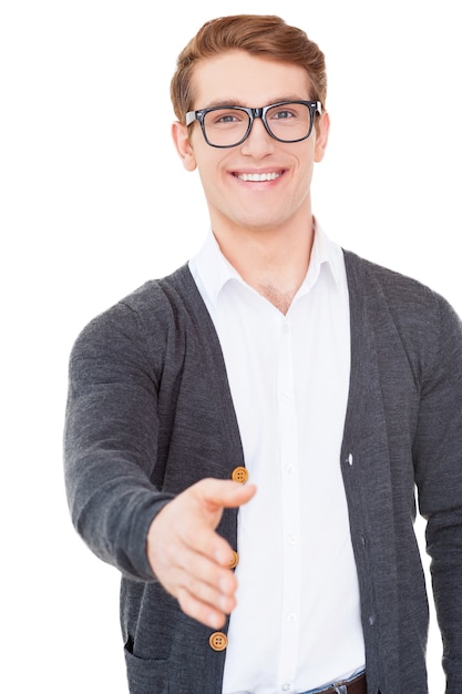 Nice to meet you! Handsome young man stretching out hand for shaking while standing isolated on white