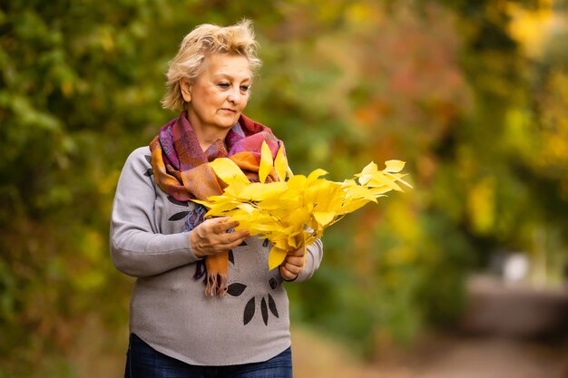 nice older woman stands on a background of yellow autumn