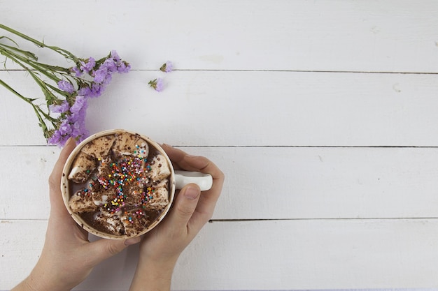 Nice picture of female hands holding a drink with marshmallows with flowers