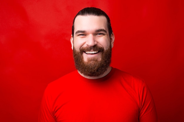 Nice picture of a man looking and smiling at the camera near a red wall