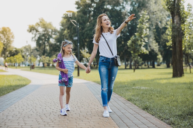 Nice place. Blonde-haired woman showing her daughter nice place for taking a ride on skateboard