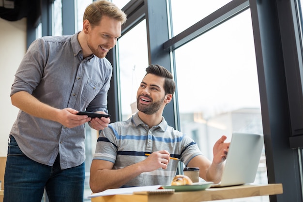 Nice pleasant smart men smiling and talking to each other while discussing their idea