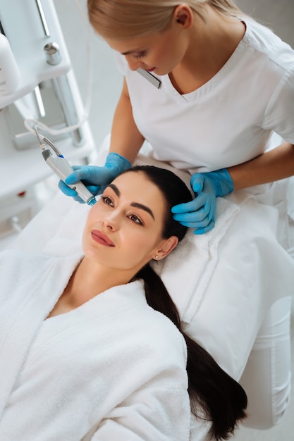 Nice pleasant woman smiling while having a beauty procedure in the beauty salon
