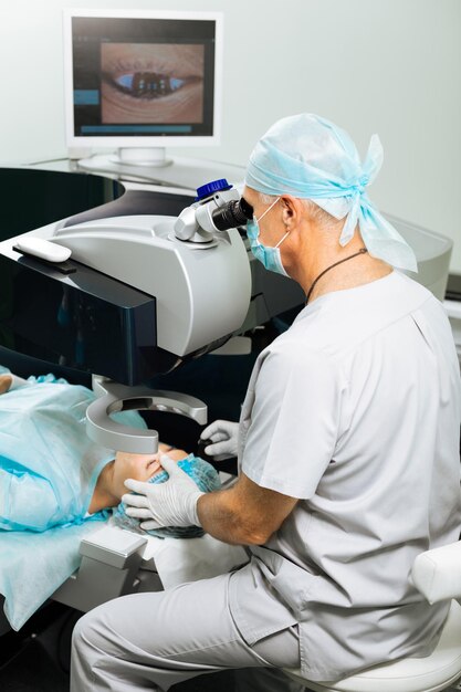 Nice professional doctor doing the medical operation while helping his patient to correct the eyesight