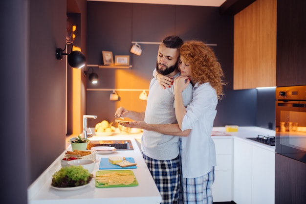 Nice red haired woman hugging her husband