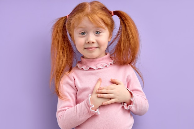 Nice redhead child girl holding hands on chest feeling gratitude or dreaming