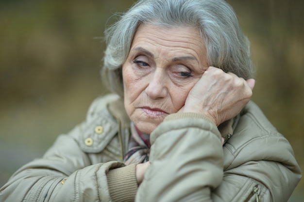 Nice sad old woman on the autumn background