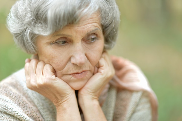 Nice sad old woman on the autumn background