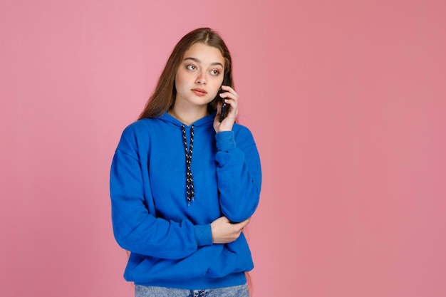 Foto bella donna seria con la faccia pensierosa che parla al cellulare mentre distoglie lo sguardo all'interno