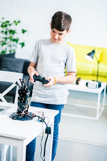 Nice singenious boy holding a remote control while testing his robotic creation