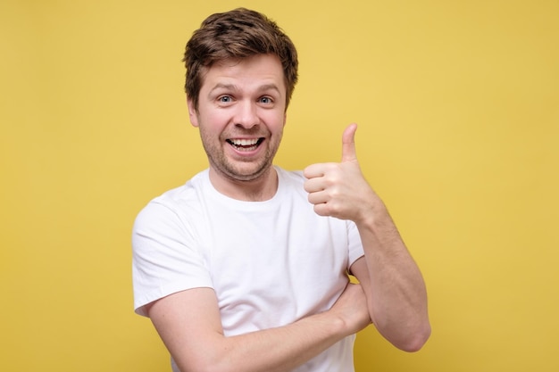 Nice smile friendly caucasian man in white tshirt giving thumbs up