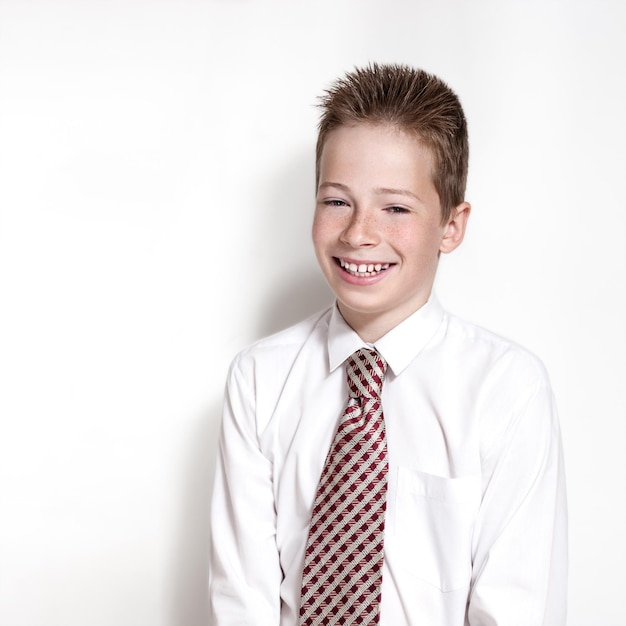 The nice smiling boy teenager in a white shirt and a tie on a white background with place for text