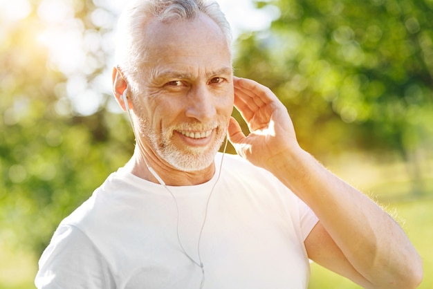 Nice sound. Positive delighted aged man wearing earphones