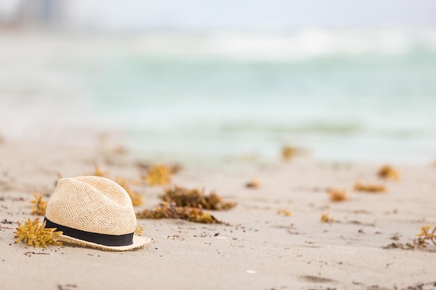 Nice straw hat laying on the sand Beautiful ocean beach background Outdoors Vacation time