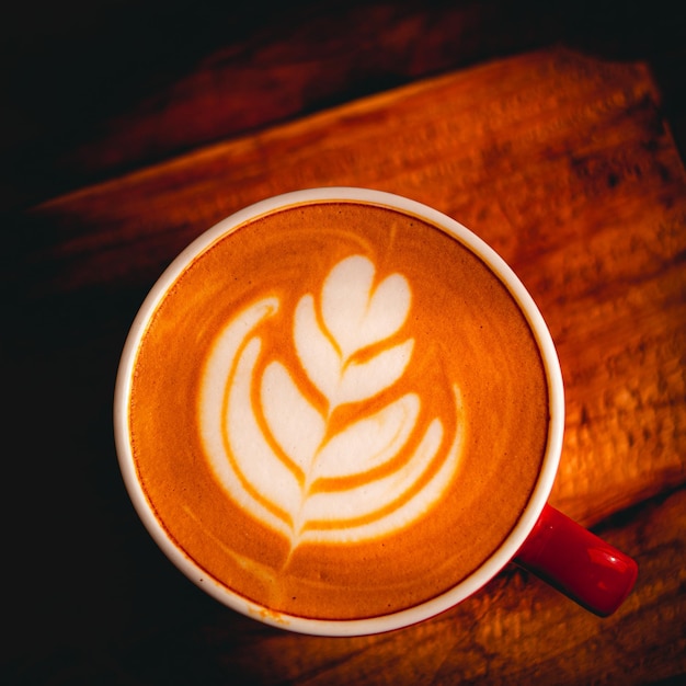 Photo nice texture of latte art on hot latte coffee milk foam in heart shape leaf tree on top of latte art from professional barista artist