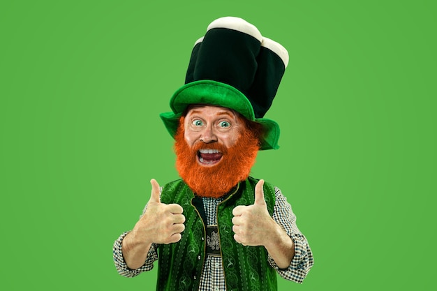 Nice, thumbs up. excited leprechaun in green suit with red\
beard on green background. funny portrait of man ready to party.\
saint patrick day, human emotions, celebration, traditional\
holidays.