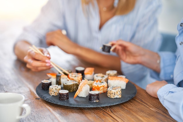Хорошие две взрослые девушки в доме едят суши
