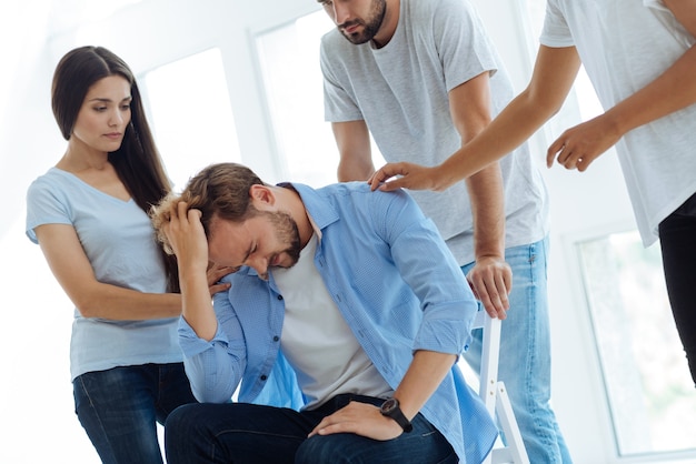 Nice unhappy cheerless man holding his hair and thinking about personal problems while having a chronic depression