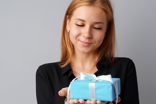Славная женщина держит в руках синюю подарочную коробку