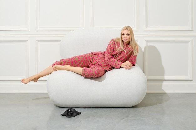 Nice woman in pink pajamas reclining on a large soft ottoman