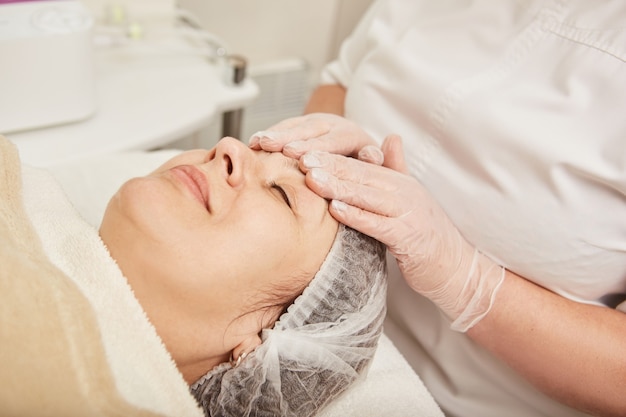 Nice woman receiving rejuvenation facial massage at wellness center