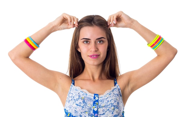 Nice woman in white Tshirt with varicoloured bracelets holding hands at her head in studio