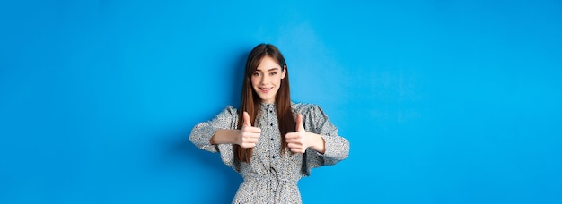 Nice work very good smiling young woman showing thumbs up to support your choice looking pleased and