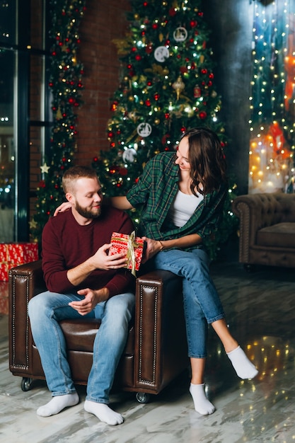 Nice young family husband and wife give gifts at the Christmas tree