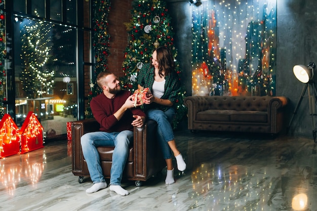 Nice young family husband and wife give gifts at the Christmas tree