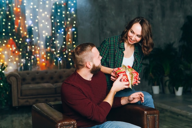 Nice young family husband and wife give gifts at the Christmas tree