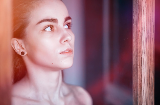 A nice young girl with wet hair behind the glass