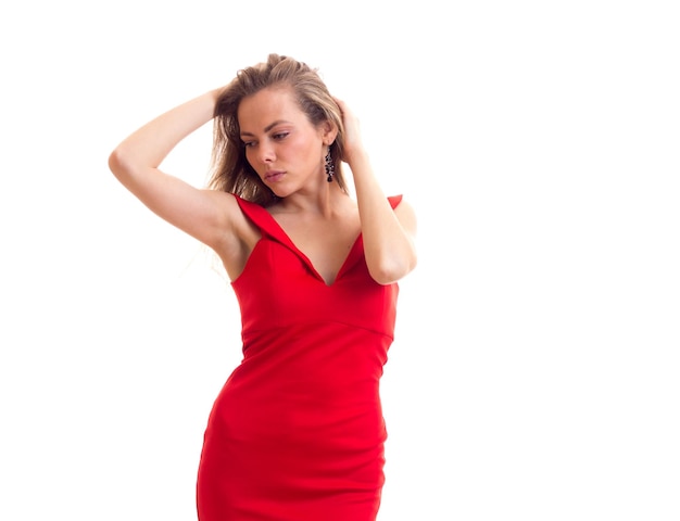 Nice young woman with long brown  hair in skimpy red dress with black earings in studio