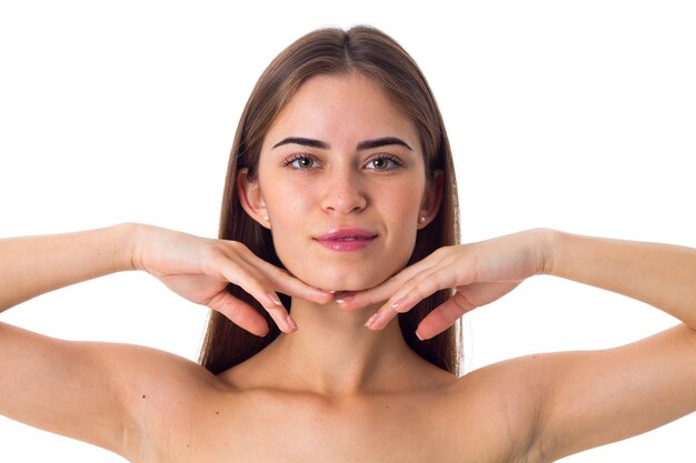 Nice young woman with long brown hair touching her face on white background in studio