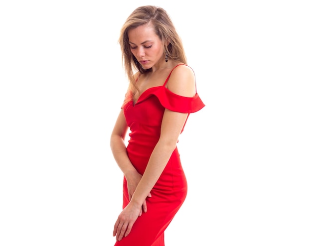 Nice young woman with long hair in skimpy red dress on white background in studio