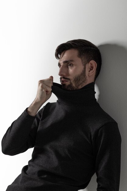 Nicelooking caucasian casually dressed man standing by the white studio wall