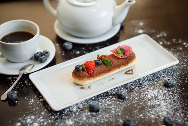 Foto dessert piacevolmente decorato con frutta, servito su un piatto bianco