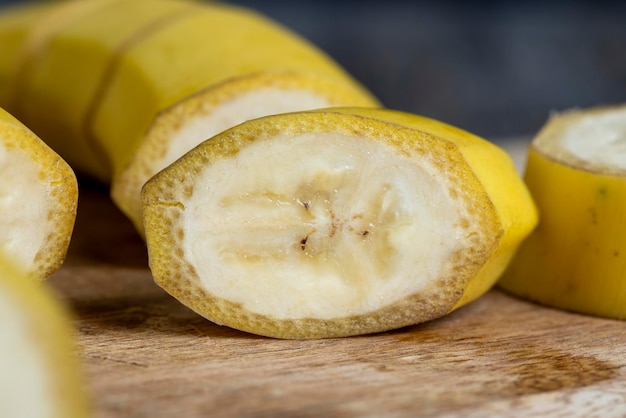 Niet geschilde rijpe gele banaan in stukjes gesneden op een plank