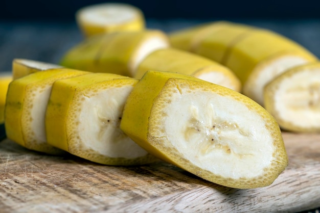 Niet geschilde rijpe gele banaan in stukjes gesneden op een plank
