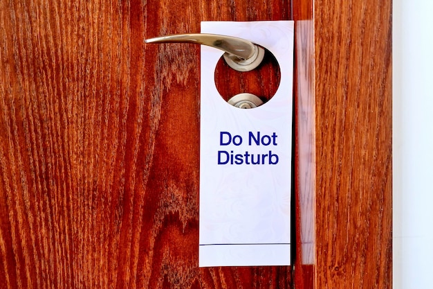 Niet storen bordje hangt aan de deurknop. Niet storen bord bij de deur van de hotelkamer. Detailopname