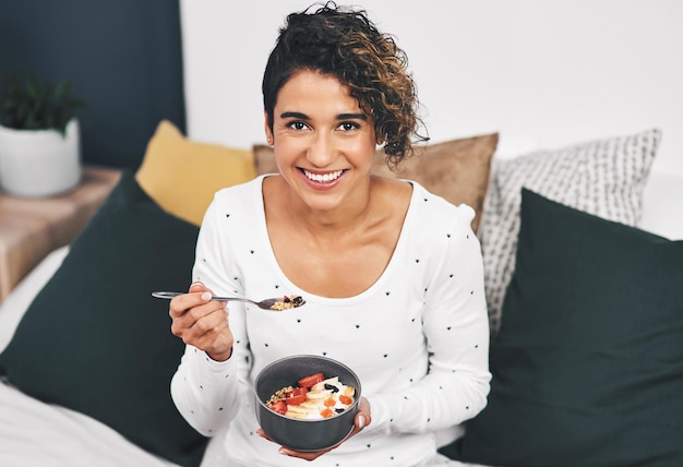 Niets is beter dan haver en fruit in de ochtend Bijgesneden portret van een aantrekkelijke jonge vrouw die een kom haver vasthoudt terwijl ze thuis op haar bed zit