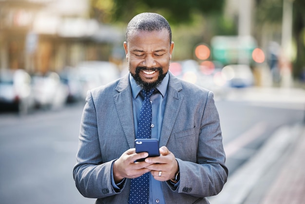 Niets maakt uw dag zo leuk als het zien van geld dat op uw rekening wordt gestort Shot van een zakenman die zijn mobiele telefoon gebruikt terwijl hij in de stad is