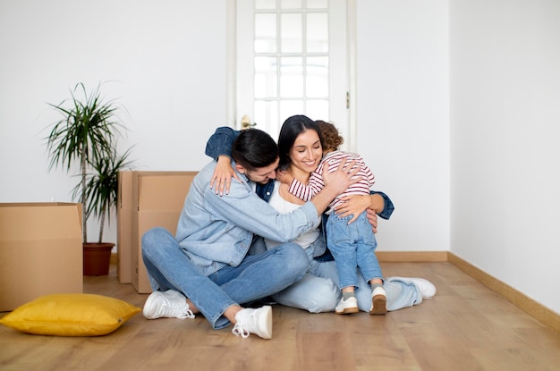 Nieuw begin gelukkig gezin van drie omarmen thuis op verhuisdag