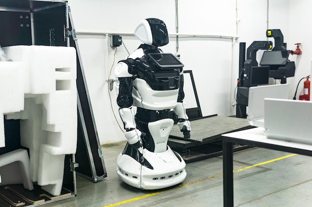 Foto nieuw geassembleerde humanoïde robot in een werkplaats wordt opgeladen voor verpakking