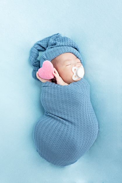 Nieuw - geboren babymeisje dat en hart slaapt houdt. Klein kind met dag dutje in bed van de ouders