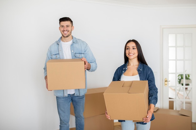 Nieuw huis Gelukkig jong stel met kartonnen dozen met bezittingen