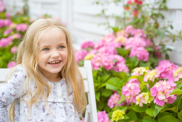 Nieuw leven concept Lente vakantie Kinderdag Klein babymeisje Klein meisje bij bloeiende bloem Zomer Moeders of vrouwendag Lentebloemen Jeugd gelukkig meisje Aangename lentedag